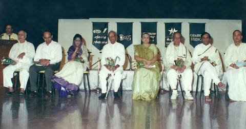 Row of seated artists and guests on stage, including Kavi Narayan Agrawal