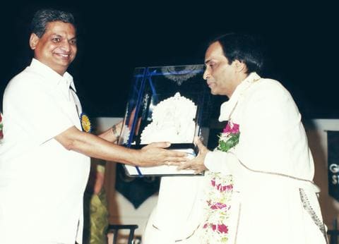 A guest presenting a crystal memento to Kavi Narayan Agrawal on stage