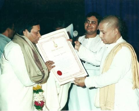 Kavi Narayan Agrawal receiving a framed certificate from ISKCON devotees