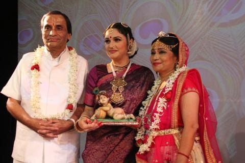 Kavi Narayan Agrawal garlanded, standing with two performers who hold a Bal Krishna figure